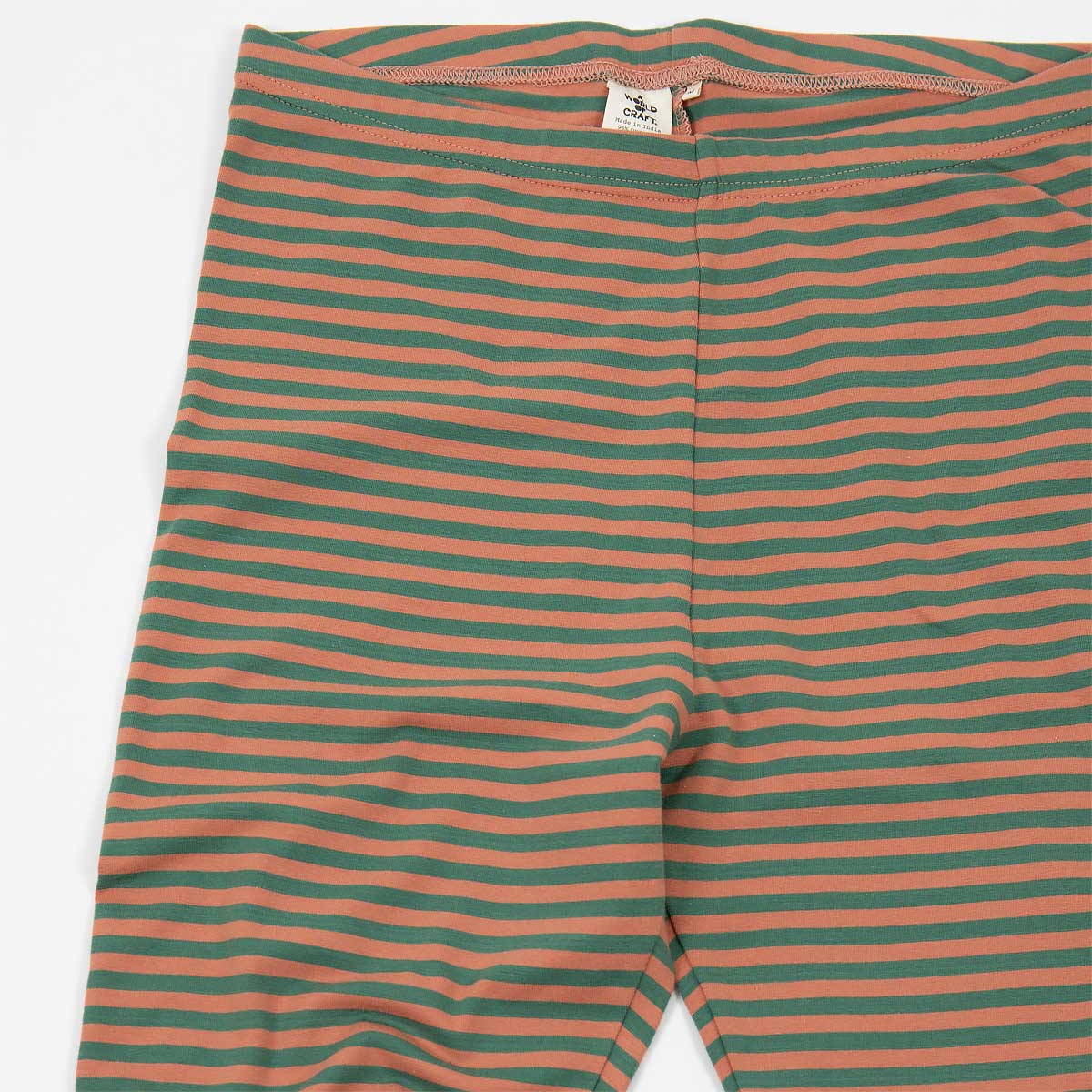 Detalj på randiga leggings i ekologisk bomull, i färgen grönt och aprikos