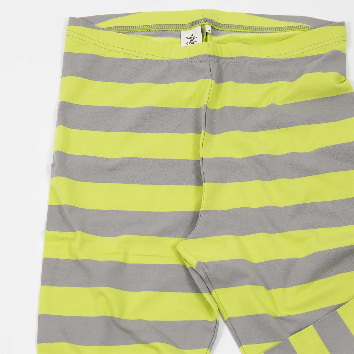 Detalj på randiga leggings i ekologisk bomull, i färgen limegult och grått