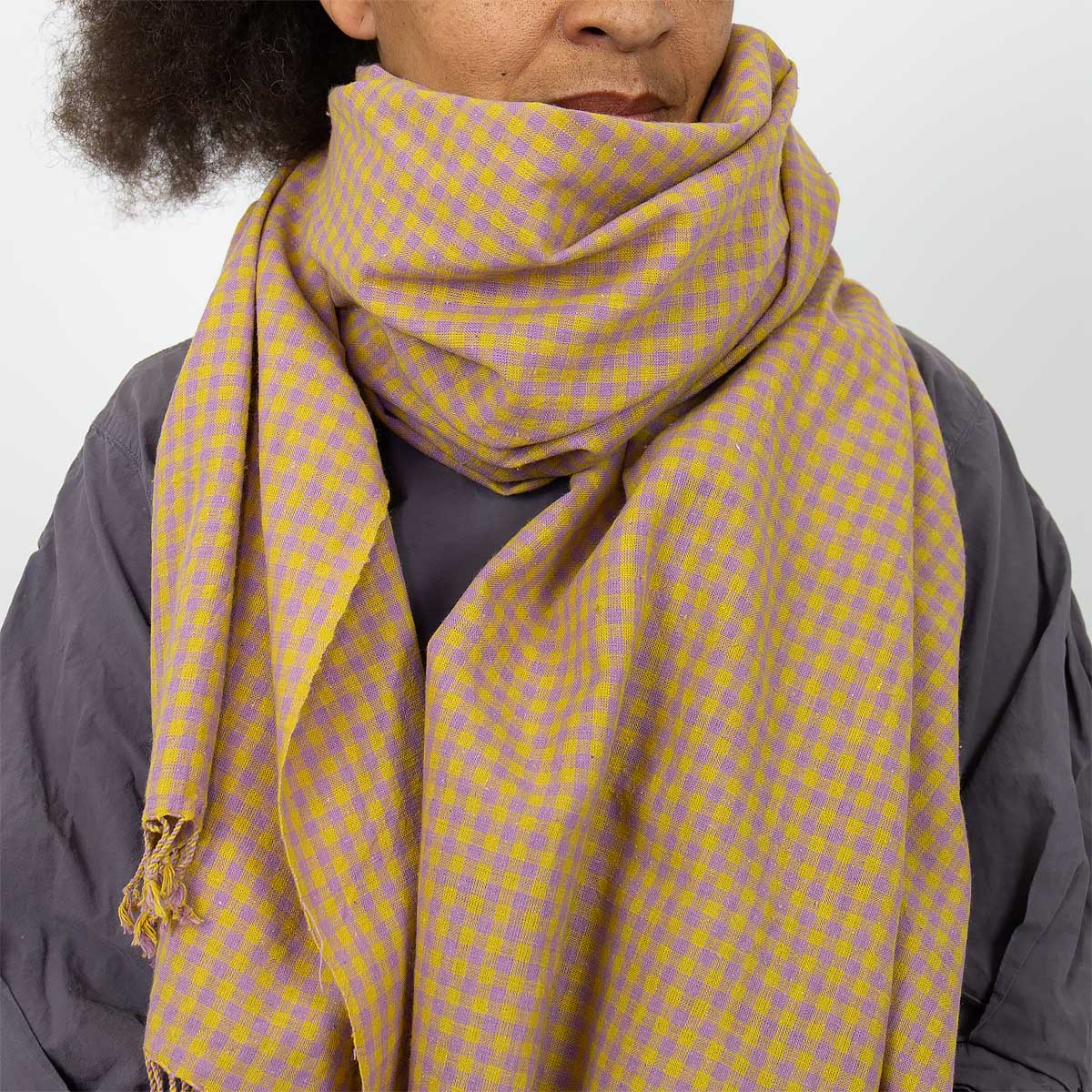 Modell bär en stor rutig sjal i lila och senap - Fair Trade