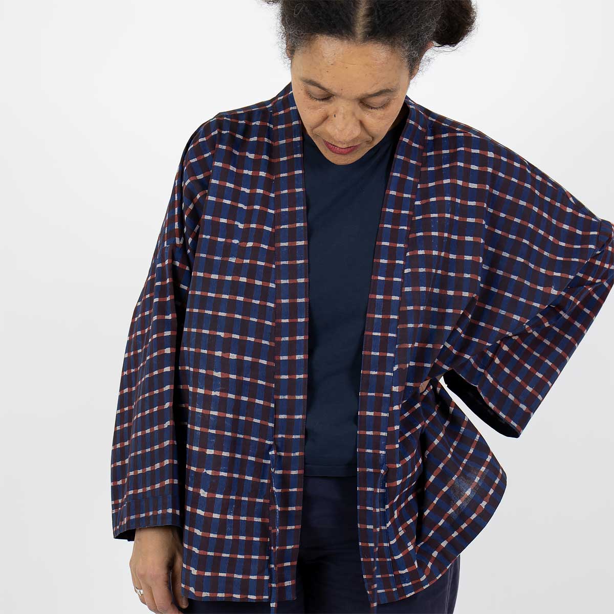 Modell bär en kort kimono med rutigt mönster, i blått och rött - Fair Trade