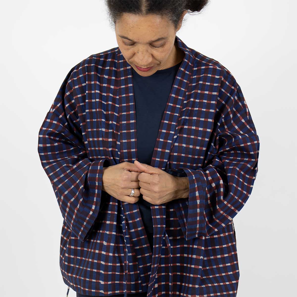 Modell bär en kort kimono med rutigt mönster, i blått och rött - Fair Trade