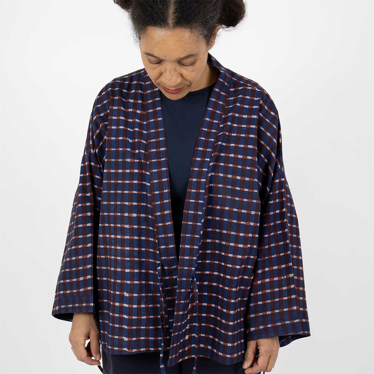 Modell bär en kort kimono med rutigt mönster, i blått och rött - Fair Trade