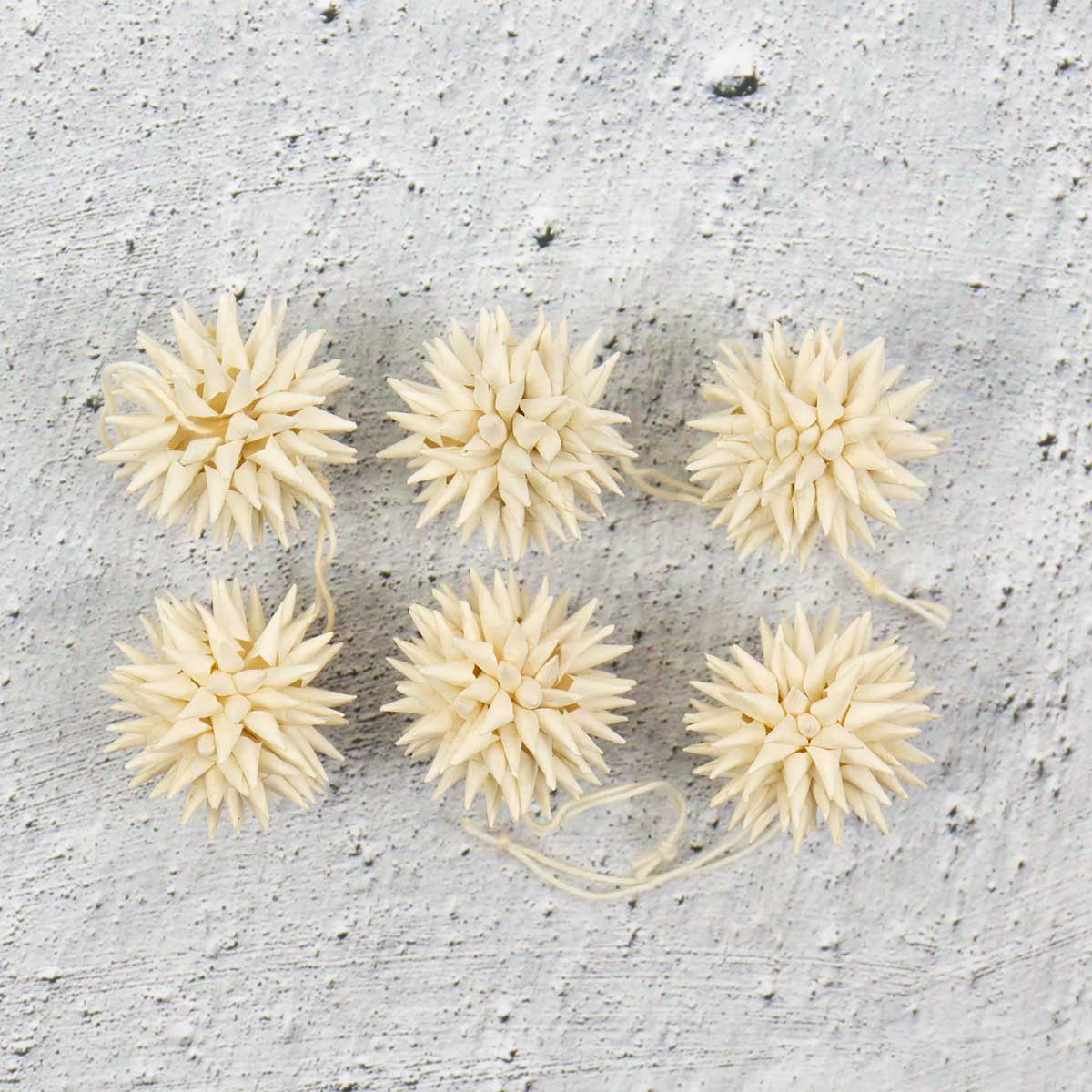 Små beige julhänge föreställande kottar