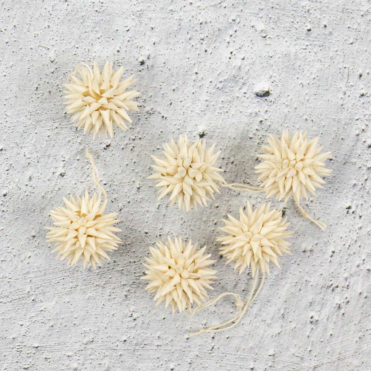 Små beige julhänge föreställande kottar