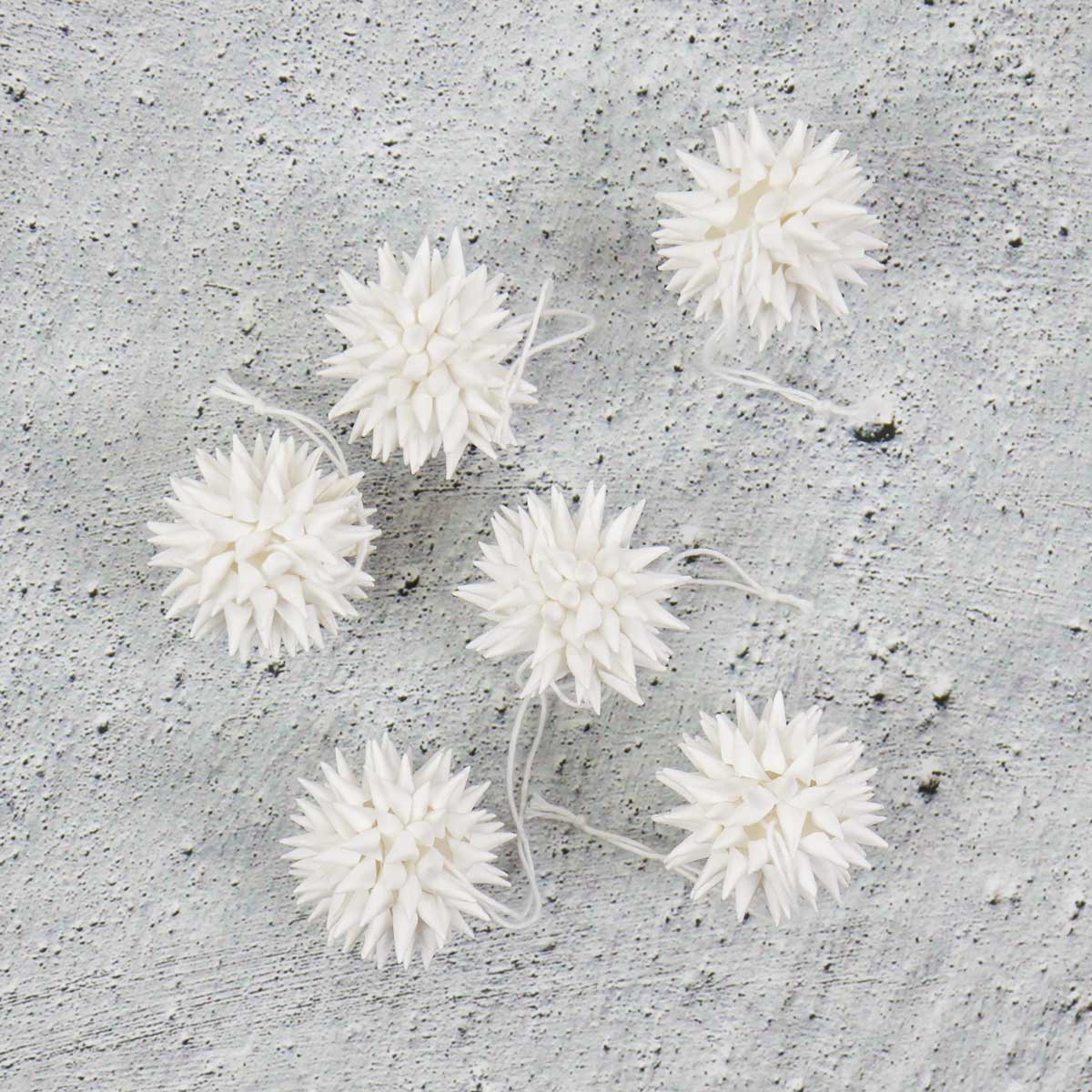 Små vita julhänge föreställande kottar