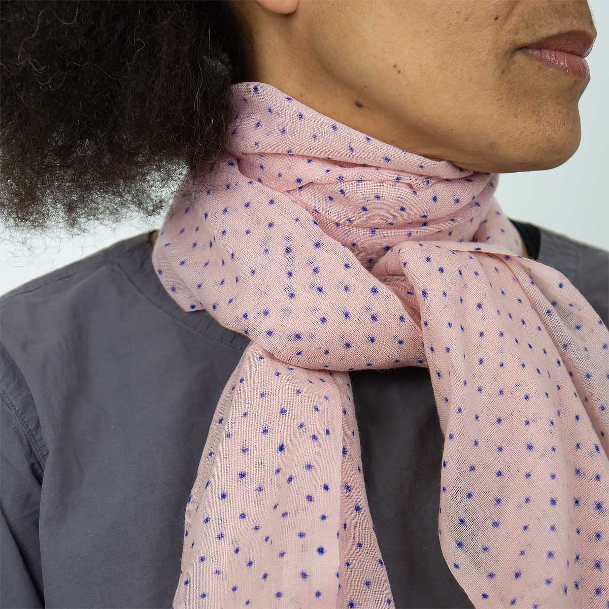 Modell bär en sjal i tunn ull, rosa med små blå stjärnor - Fair Trade