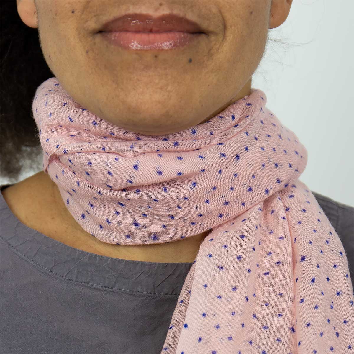 Modell bär en sjal i tunn ull, rosa med små blå stjärnor - Fair Trade