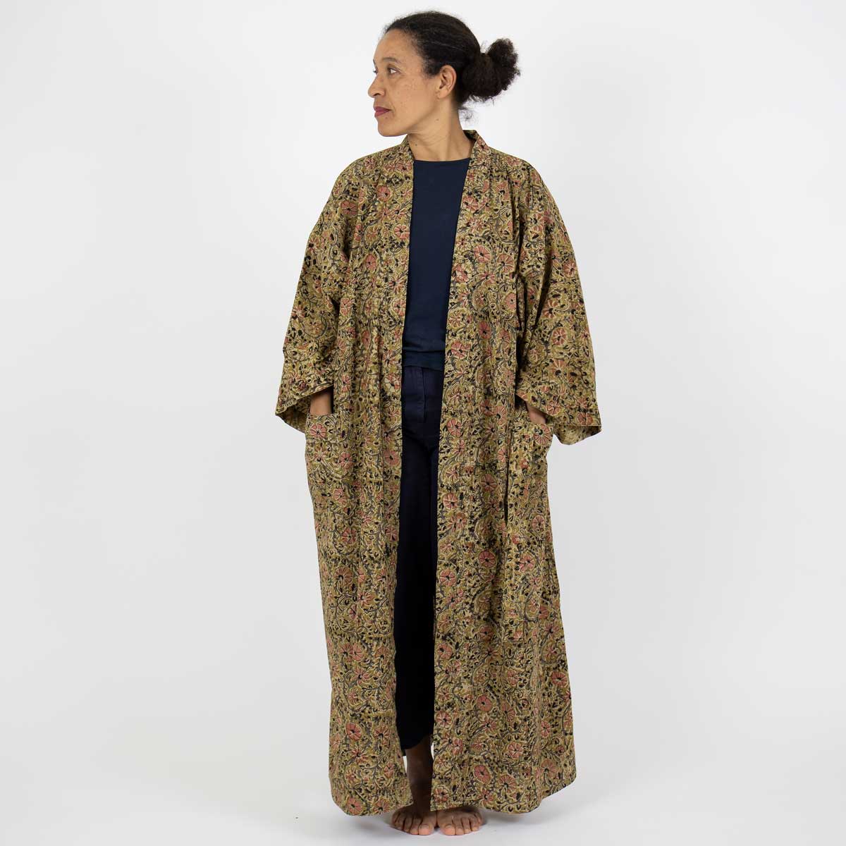 Modell bär hellång kimono i senapsgult blommönster - Fair Trade