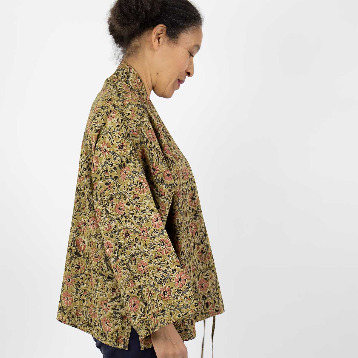 Modell bär en kort kimono i senapsgult blommönster - Fair Trade