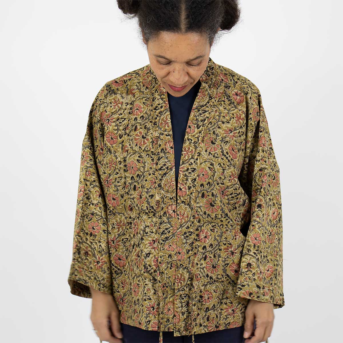 Modell bär en kort kimono i senapsgult blommönster - Fair Trade