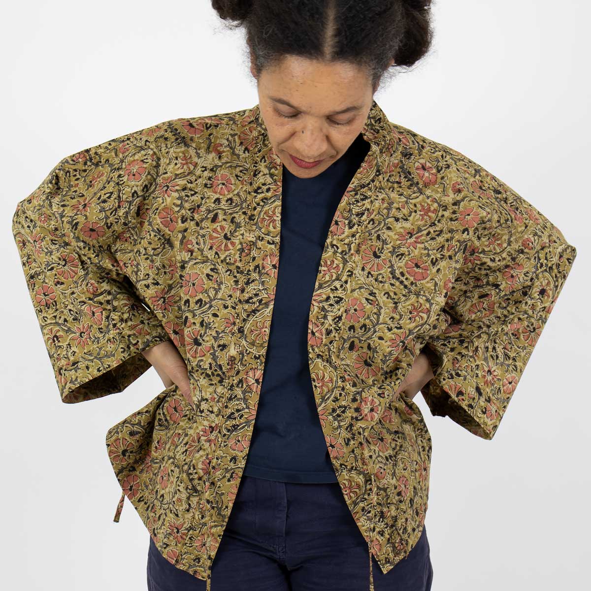 Modell bär en kort kimono i senapsgult blommönster - Fair Trade