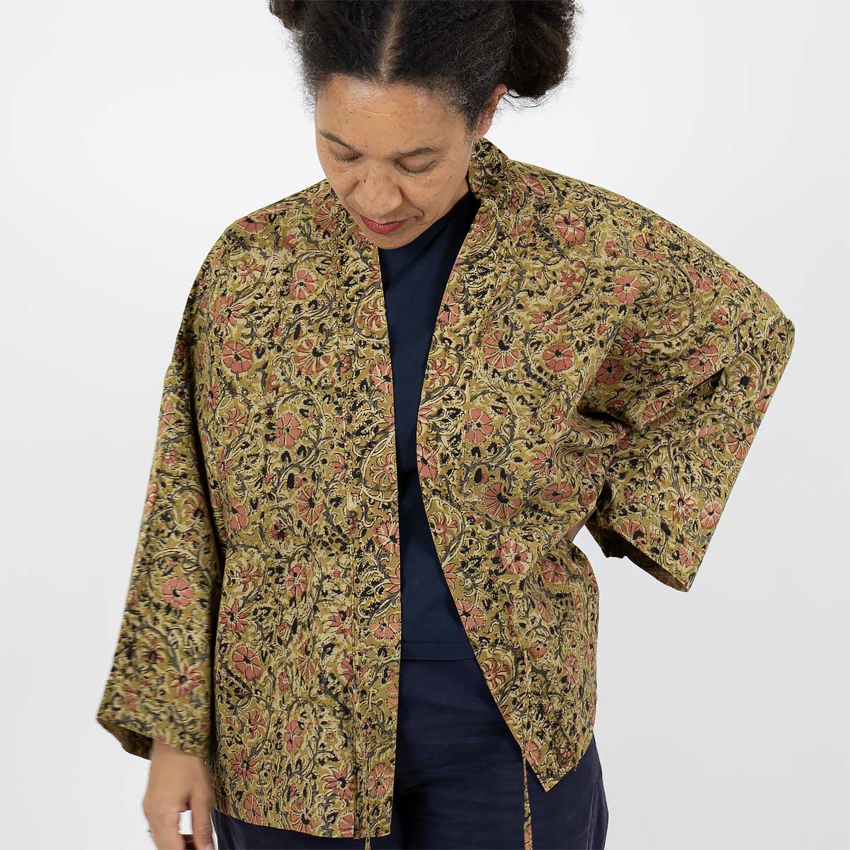 Modell bär en kort kimono i senapsgult blommönster - Fair Trade