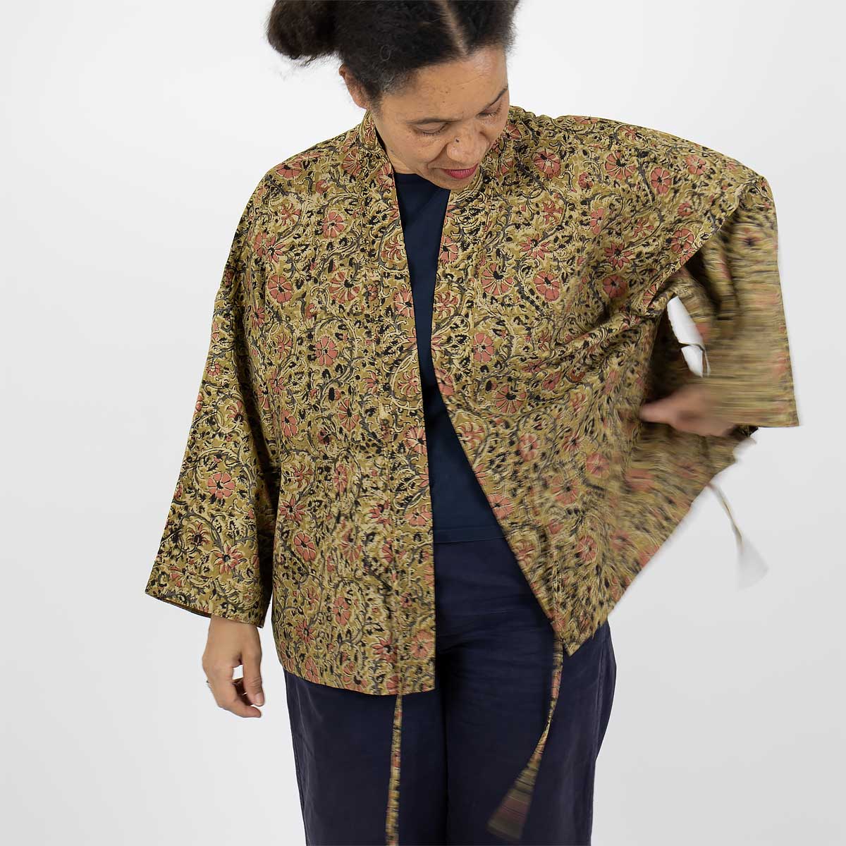 Modell bär en kort kimono i senapsgult blommönster - Fair Trade