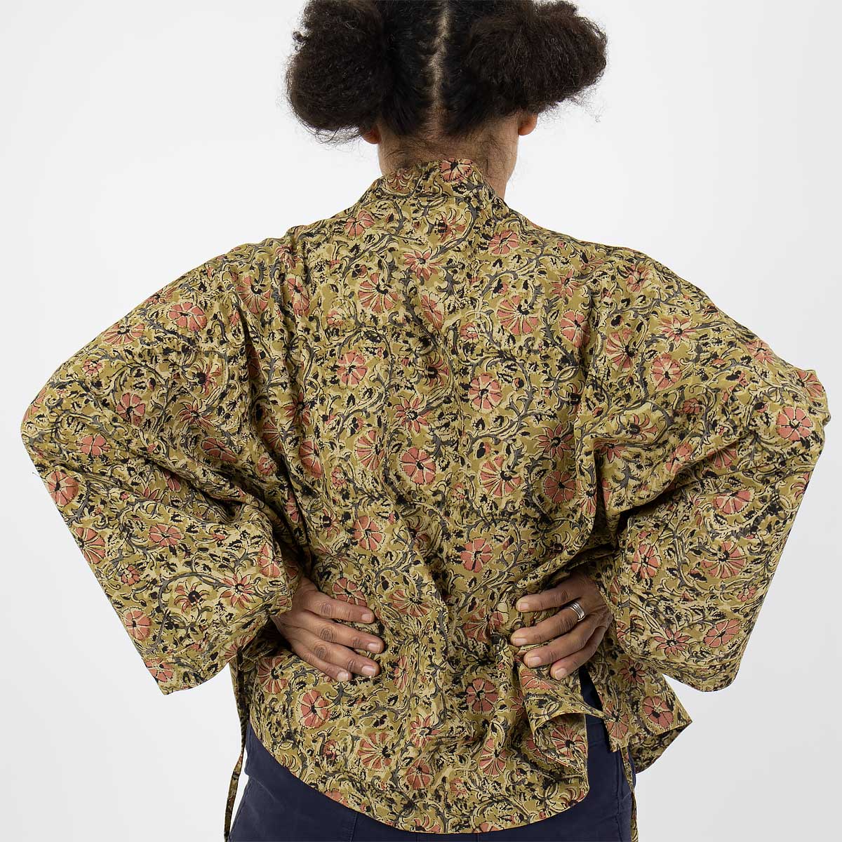 Modell bär en kort kimono i senapsgult blommönster - Fair Trade