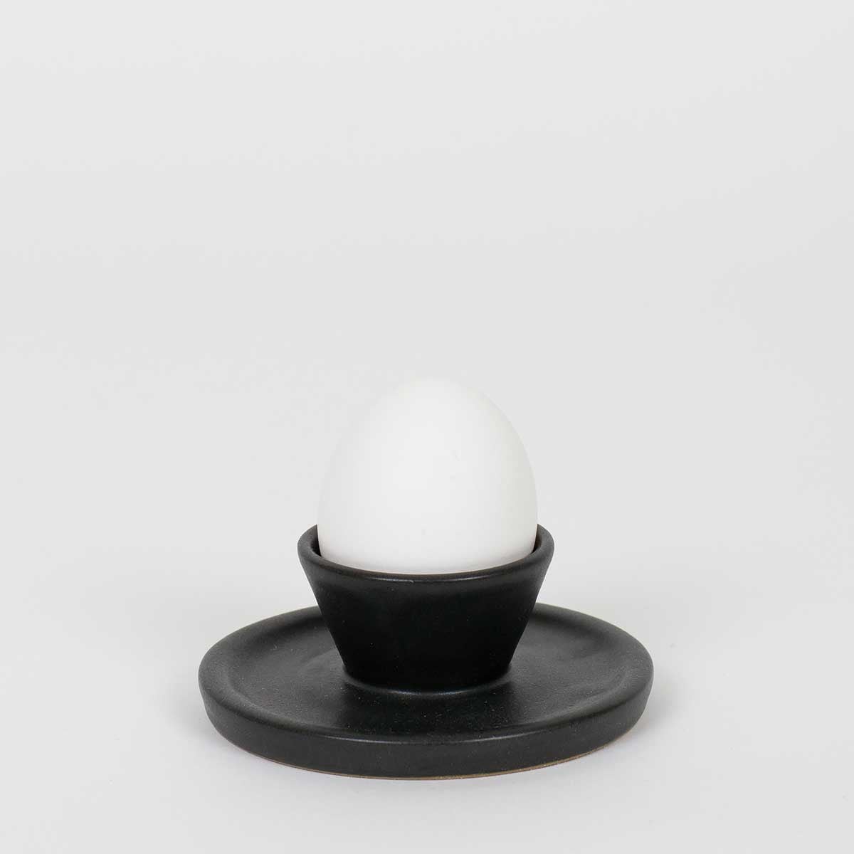 Svart äggkopp med ett ägg i