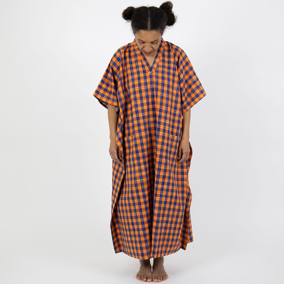 Modell bär en hellång kaftan i rutigt mönster, orange och blått - Fair Trade