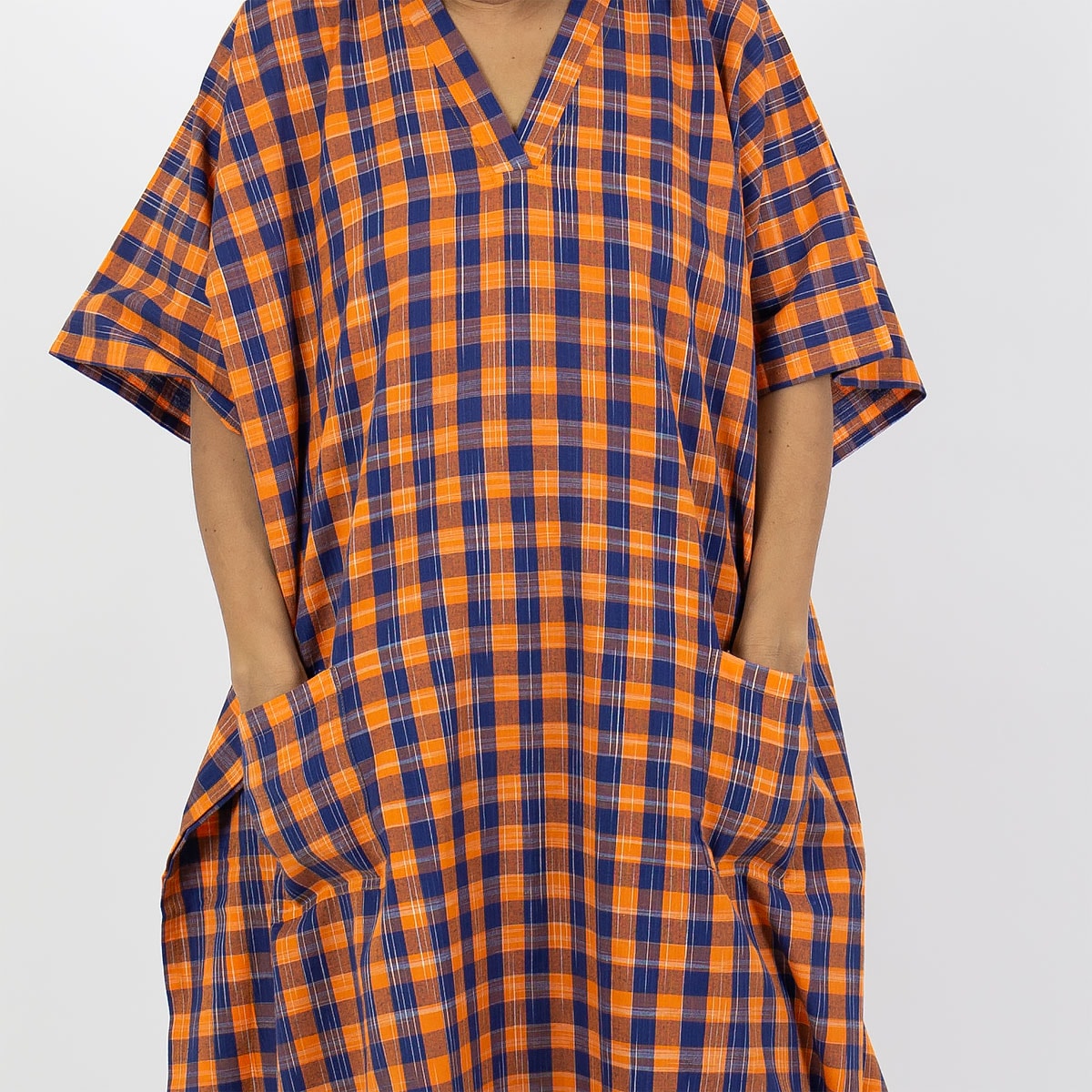 Modell bär en hellång kaftan i rutigt mönster, orange och blått - Fair Trade