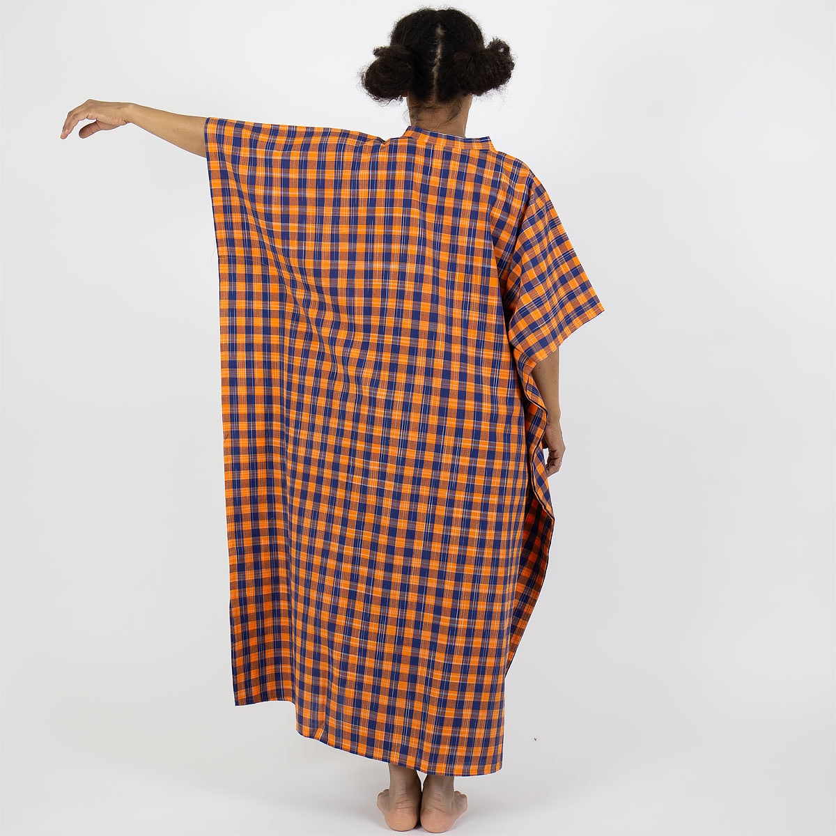 Modell bär en hellång kaftan i rutigt mönster, orange och blått - Fair Trade